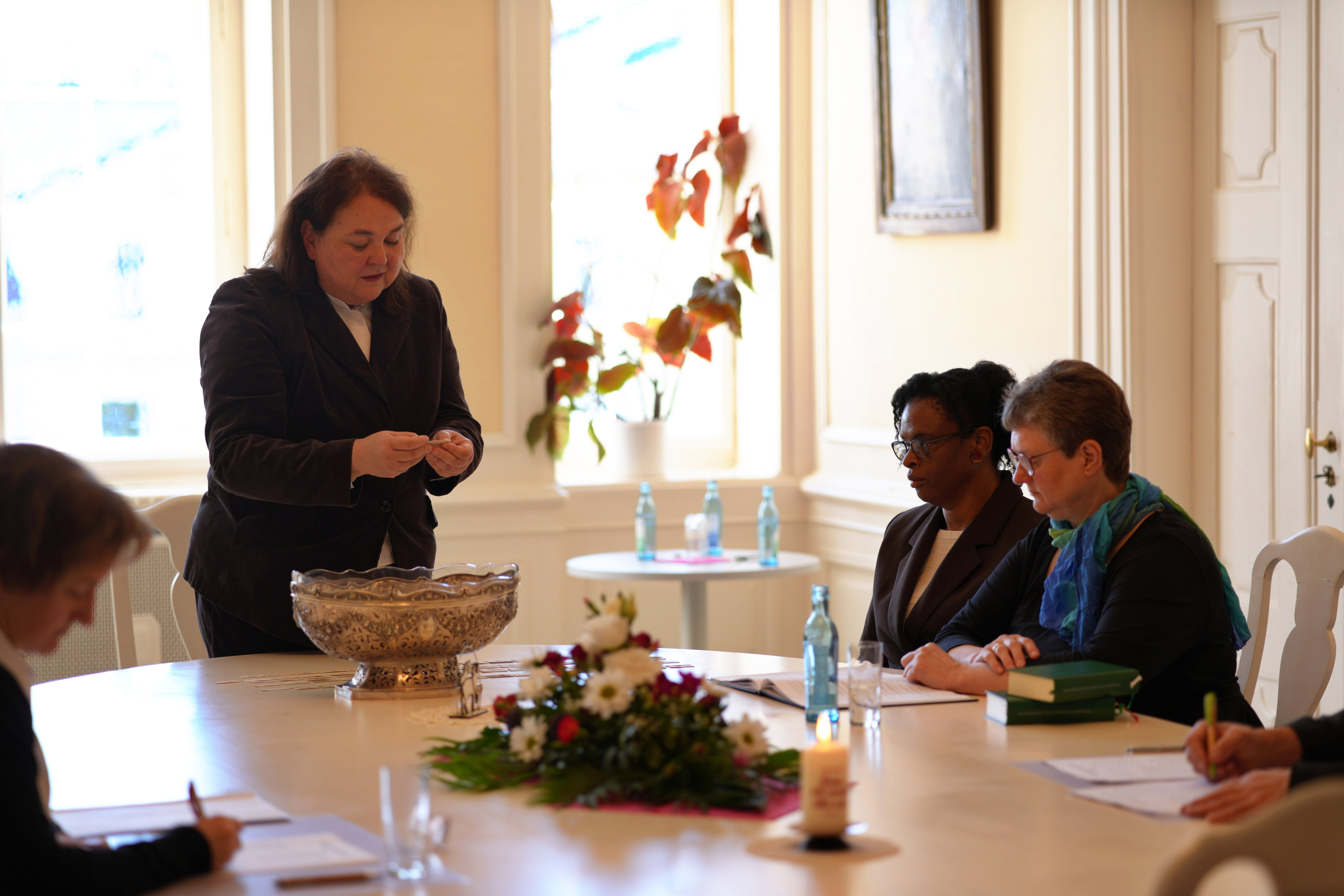 Eine Frau zieht ein Losung, zwei Frauen sitzen daneben und protokollieren